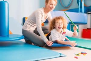 A boy with bowel bladder dysfunction does core exercise with pediatric therapist